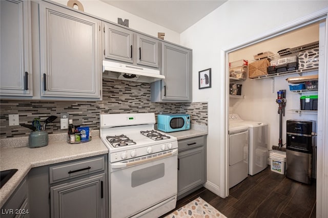 kitchen with washing machine and dryer, dark hardwood / wood-style flooring, backsplash, white appliances, and gray cabinets