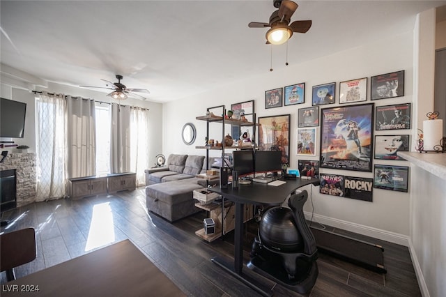 office featuring ceiling fan, a stone fireplace, and dark hardwood / wood-style flooring