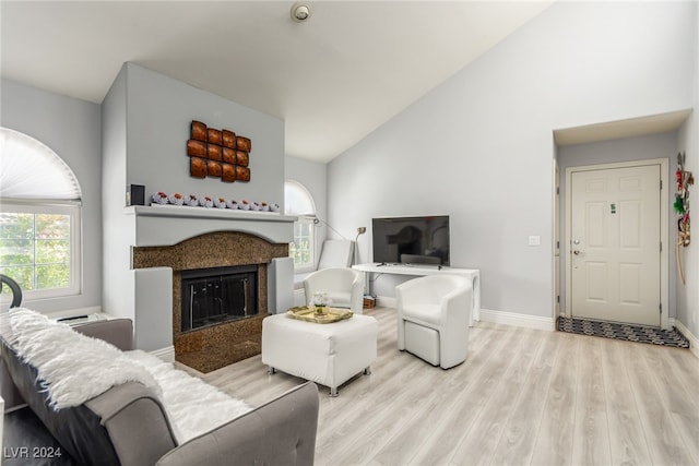 living room featuring high vaulted ceiling, a high end fireplace, and light hardwood / wood-style flooring