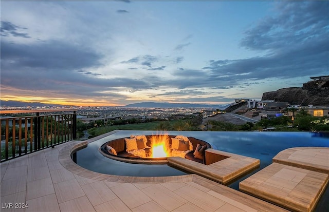 pool at dusk with a mountain view and an outdoor fire pit