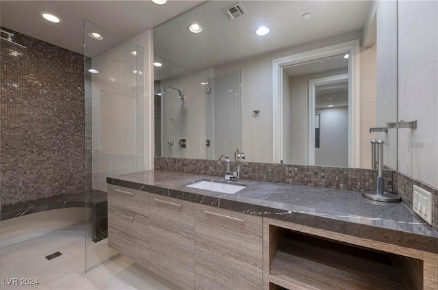 bathroom with vanity, a shower with shower door, tile patterned flooring, and decorative backsplash