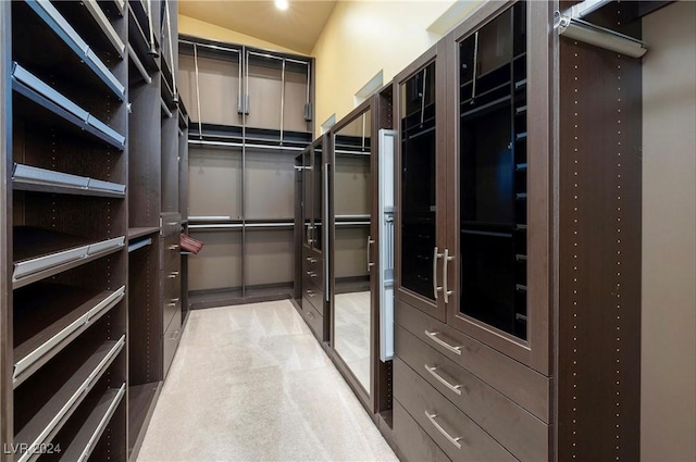 spacious closet with light carpet and vaulted ceiling