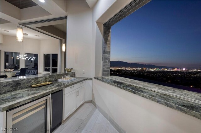 balcony at dusk featuring a mountain view, beverage cooler, and an outdoor kitchen