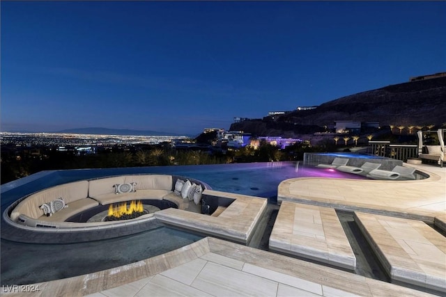 pool at twilight featuring a patio area and pool water feature