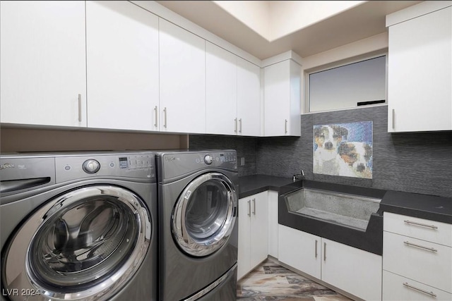 clothes washing area featuring sink, washing machine and dryer, and cabinets