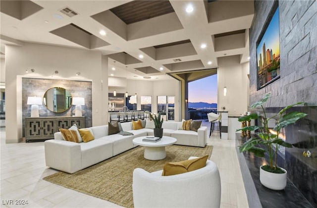 living room with a high ceiling, coffered ceiling, and a large fireplace