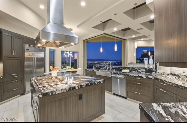 kitchen featuring island range hood, appliances with stainless steel finishes, kitchen peninsula, pendant lighting, and dark stone counters