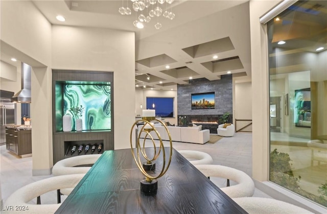 dining area featuring coffered ceiling, an inviting chandelier, beamed ceiling, a towering ceiling, and a fireplace