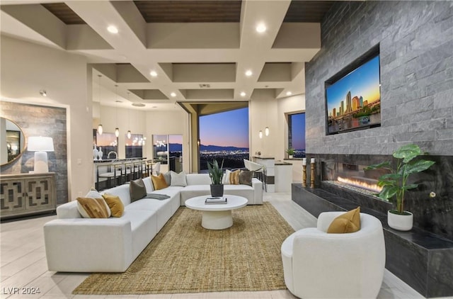 living room with coffered ceiling, a large fireplace, beam ceiling, and a towering ceiling