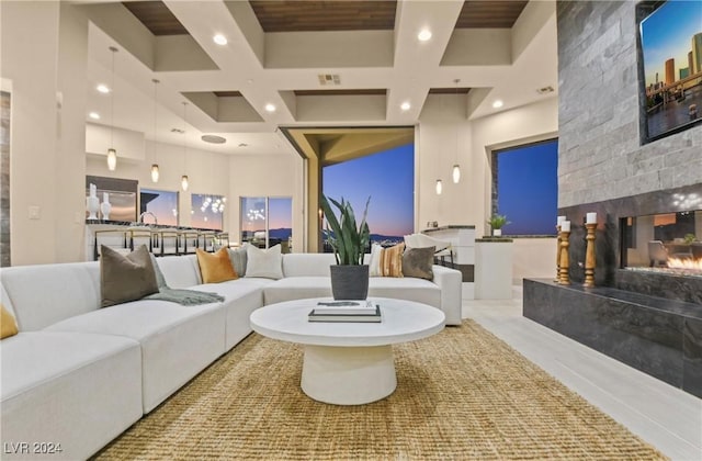 interior space with beam ceiling, coffered ceiling, a high end fireplace, and a towering ceiling