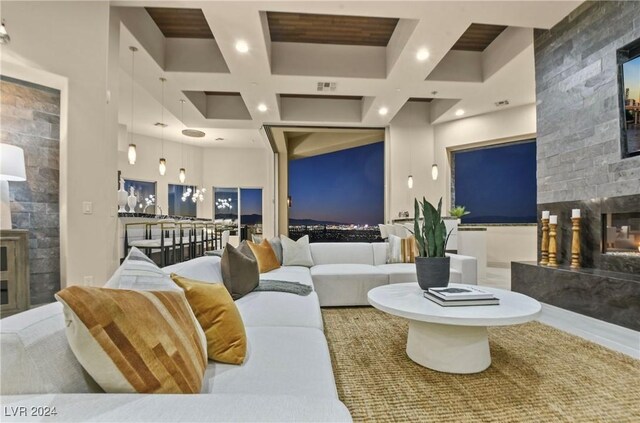 living room featuring coffered ceiling, a fireplace, beam ceiling, and a high ceiling