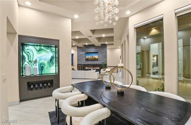 dining room with an inviting chandelier, beam ceiling, a high ceiling, coffered ceiling, and a large fireplace