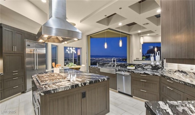 kitchen with a spacious island, decorative light fixtures, appliances with stainless steel finishes, island exhaust hood, and dark stone counters