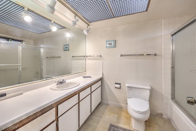 full bathroom featuring tile patterned flooring, vanity, toilet, and combined bath / shower with glass door