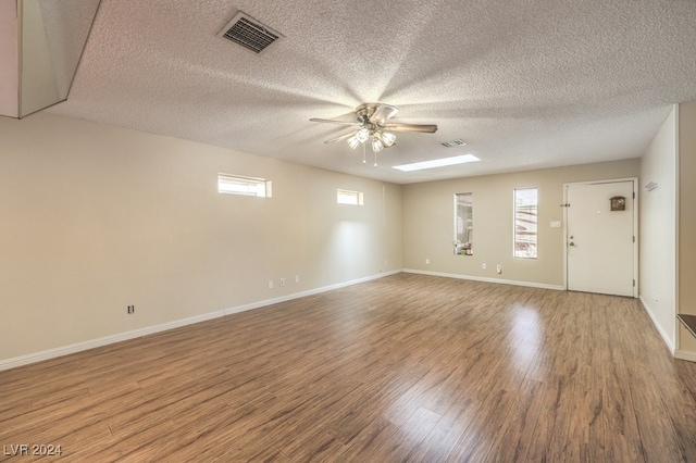 unfurnished room featuring wood-type flooring, a textured ceiling, and a healthy amount of sunlight