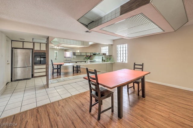 dining space with a textured ceiling, light hardwood / wood-style floors, and sink