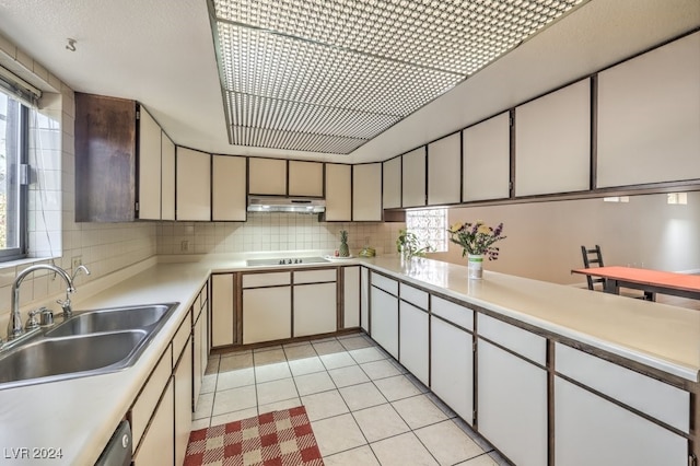 kitchen featuring sink, cooktop, stainless steel dishwasher, decorative backsplash, and light tile patterned flooring