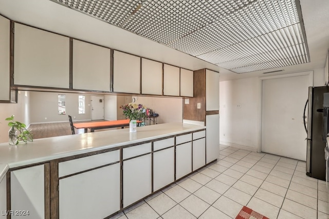 kitchen with white cabinets, stainless steel refrigerator, and light tile patterned flooring