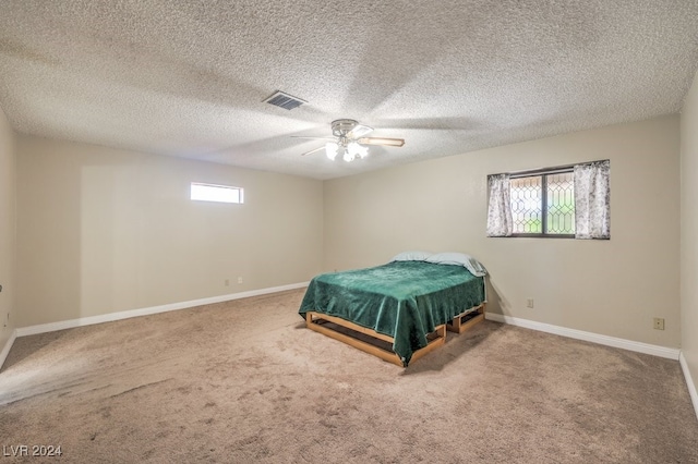 carpeted bedroom featuring multiple windows, ceiling fan, and a textured ceiling