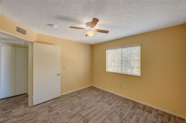 unfurnished bedroom featuring ceiling fan, light wood-type flooring, a textured ceiling, and a closet