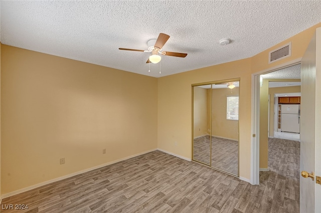 unfurnished room with ceiling fan, light hardwood / wood-style floors, and a textured ceiling