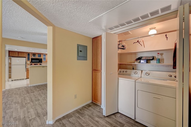 laundry room with washer and dryer, a textured ceiling, electric panel, and light hardwood / wood-style flooring