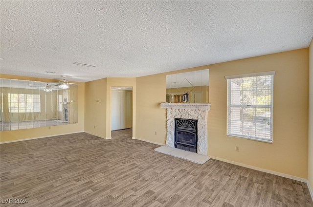 unfurnished living room featuring hardwood / wood-style flooring, ceiling fan, and a textured ceiling