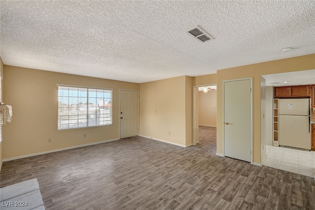 spare room with a textured ceiling and light wood-type flooring