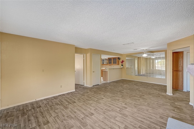 unfurnished living room with ceiling fan, light hardwood / wood-style floors, and a textured ceiling