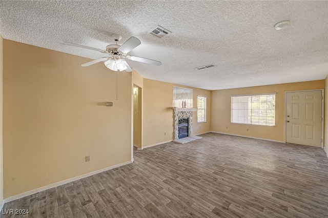 unfurnished living room with ceiling fan, hardwood / wood-style floors, and a textured ceiling