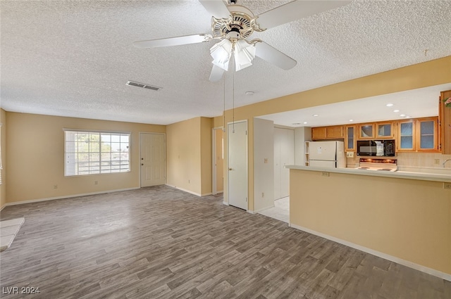 unfurnished living room with a textured ceiling, light wood-type flooring, and ceiling fan