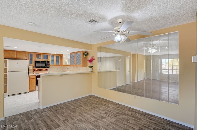 kitchen with kitchen peninsula, a textured ceiling, white appliances, ceiling fan, and light hardwood / wood-style floors