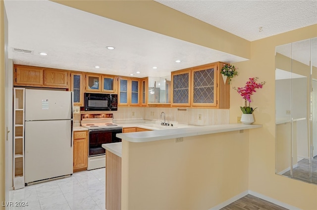 kitchen featuring white appliances, sink, a textured ceiling, a kitchen bar, and kitchen peninsula