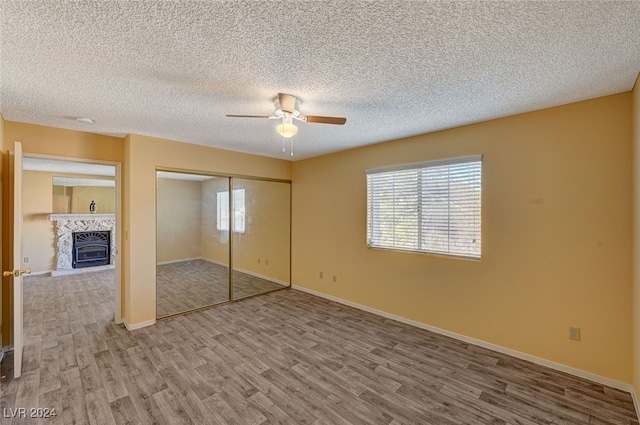 unfurnished bedroom with a textured ceiling, a closet, hardwood / wood-style flooring, and ceiling fan