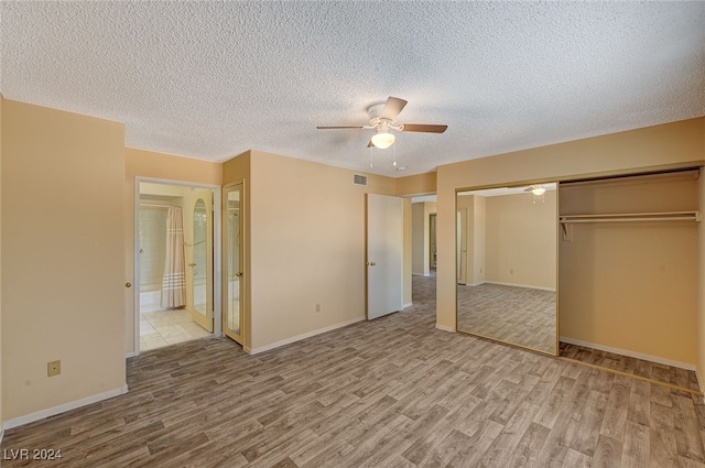 unfurnished bedroom with a textured ceiling, a closet, light hardwood / wood-style floors, and ceiling fan