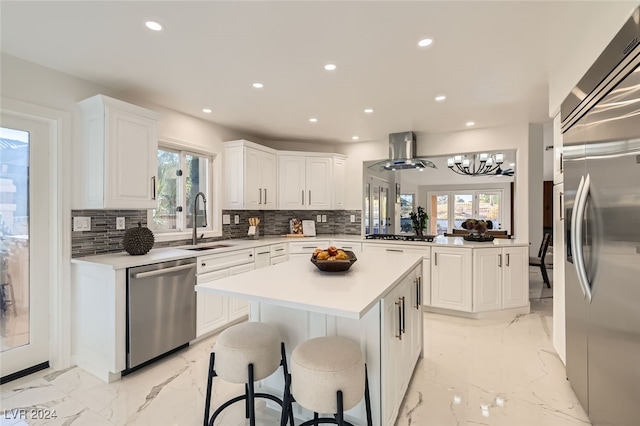 kitchen featuring sink, tasteful backsplash, a kitchen island, kitchen peninsula, and stainless steel appliances