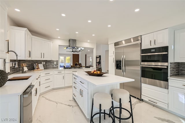 kitchen featuring white cabinets, decorative backsplash, island range hood, and stainless steel appliances