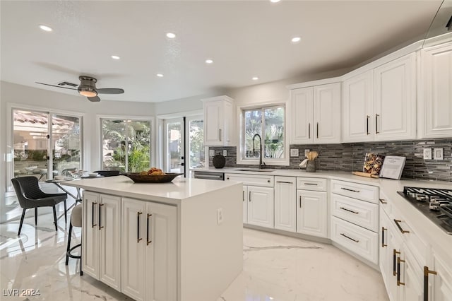 kitchen featuring white cabinets, decorative backsplash, a kitchen island, and sink