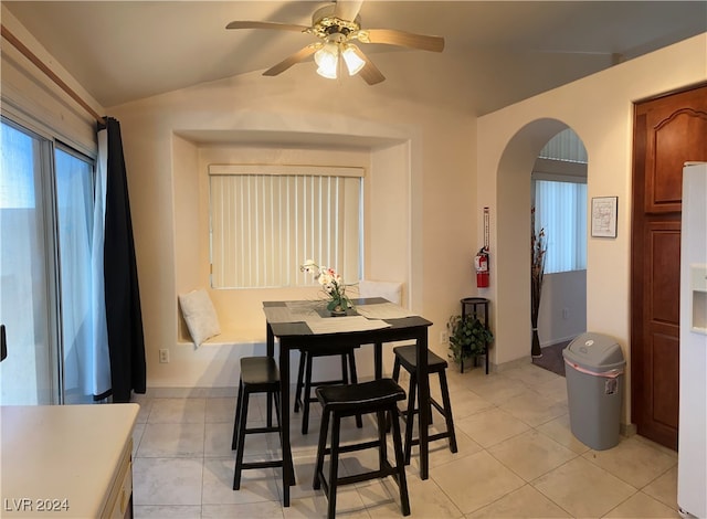 tiled dining room with ceiling fan and vaulted ceiling