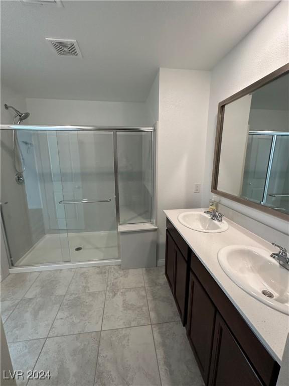 full bath with a shower with door, visible vents, and a sink