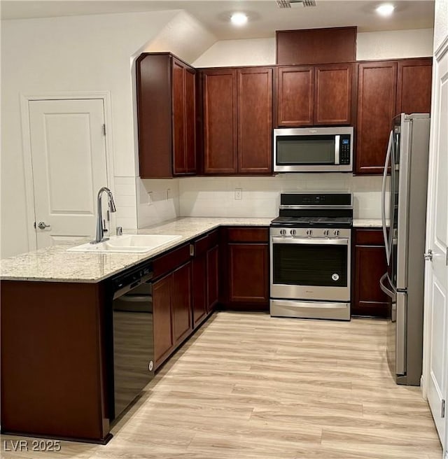 kitchen featuring stainless steel appliances, light stone countertops, sink, and light hardwood / wood-style flooring