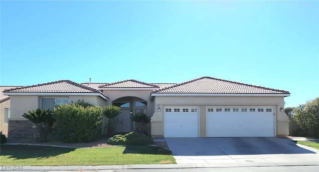 mediterranean / spanish-style home featuring concrete driveway, a tile roof, an attached garage, a front lawn, and stucco siding