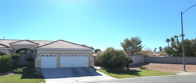 view of front of home with stucco siding, an attached garage, fence, driveway, and a tiled roof