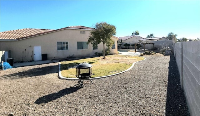 rear view of property with a tile roof, a fenced backyard, a patio, and stucco siding