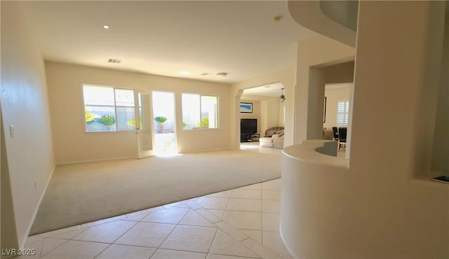 entryway featuring light carpet, baseboards, visible vents, a fireplace, and light tile patterned flooring