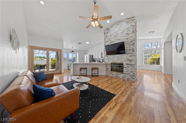 living room with a fireplace, light hardwood / wood-style flooring, ceiling fan, and lofted ceiling