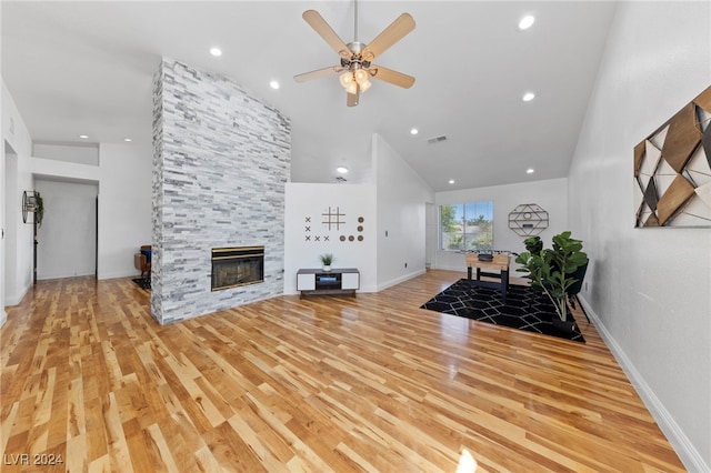 living room featuring a large fireplace, high vaulted ceiling, light hardwood / wood-style flooring, and ceiling fan