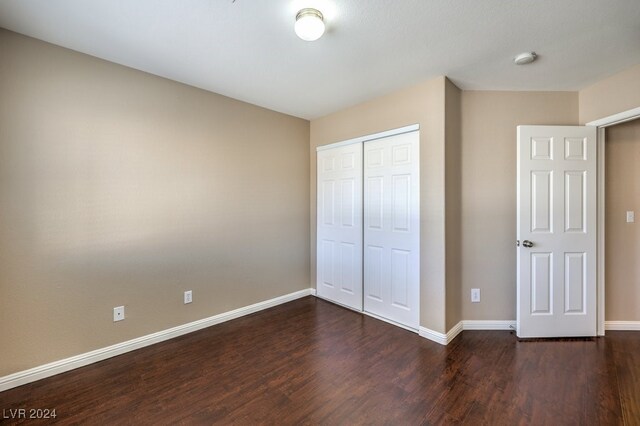 unfurnished bedroom featuring dark hardwood / wood-style floors and a closet