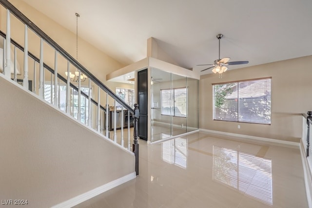 tiled entrance foyer featuring ceiling fan with notable chandelier and high vaulted ceiling