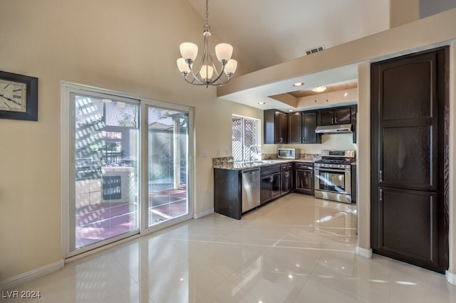 kitchen with sink, hanging light fixtures, light stone counters, dark brown cabinets, and appliances with stainless steel finishes